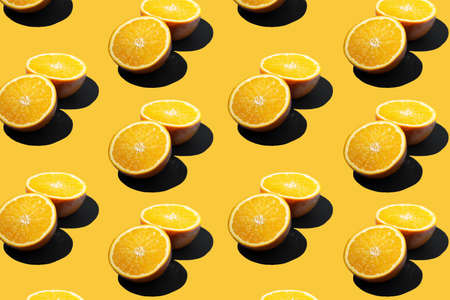 A hard light pattern of a half of an orange on a seamless yellow backgroundの写真素材