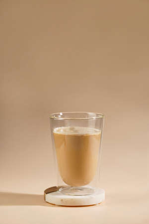 a glass with milk coffee on seamless beige colored backgroundの写真素材