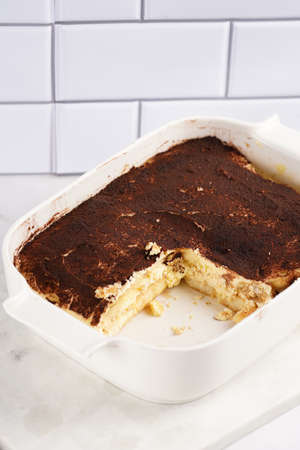 A piece of italian dessert tiramisu made of ladyfinger biscuits, mascarpone cheese, espresso on white marble backgroundの写真素材