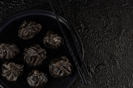 Traditional Georgian dish, khinkali Kalakuri, black dumplings stuffed with minced meat on black plate on black textured backgroundの写真素材