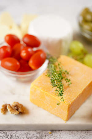 Cheese platter with organic cheeses - blue cheese cheddar, emmantal, french soft cheese with strong smell, italian parmesan, grapes, tomatoes, olives, nuts and crackers on marble boardの写真素材