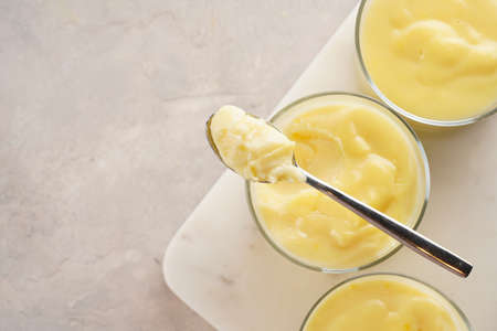 Creamy french vanilla pudding in glass on marble board on gray neutral background