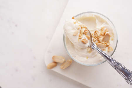 Creamy dairy yoghurt dessert with mascarpone, cream cheese and peanut butter in glasses on a marble tray with a tea spoonの写真素材