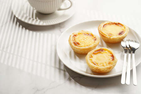 Traditional portuguese vanilla pudding puff pastry pastel de nata on black oven rack on white plate...