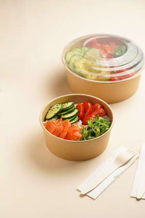 Trendy wholesome dish poke or buddha bowl - rice, wakame seaweed, tomatoes, cucumber, and red fish...