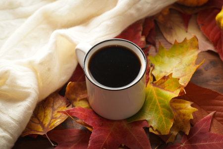 Two white cups with black coffee in a cozy autumn setting with red, yellow and orange leaves,...