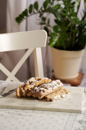 Traditional German Christmas pastry stollen on a marble cutting board, coffee mug, butter plate on...