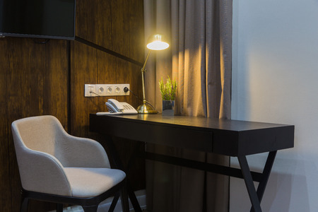 a workplace in a hotel or at home - a lamp is included, an armchair is a chair, a desk, a telephone and a lamp on the deskの写真素材