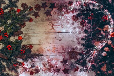 Christmas background with fir twigs, red berries, cones and Xmas decoration, lights on a wooden...