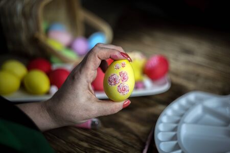 Woman hands is holding eggs with floral patterns. Preparing for Easter. Artist paints an Easter egg....