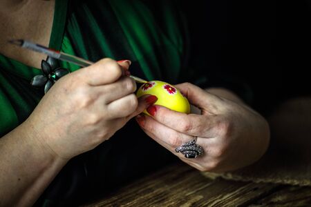 Holidays, traditional concept - close up of woman hands coloring Easter eggs with brush. Preparation for Easter. Close-up. Horizontal orientation. Copy space.の写真素材
