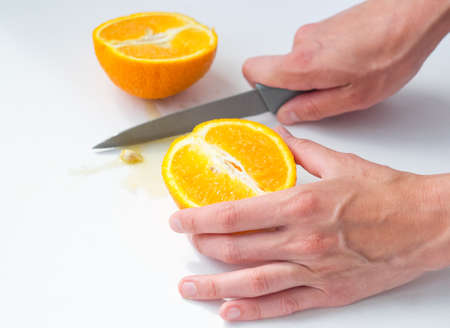 women's hands cut an orange with a knifeの写真素材