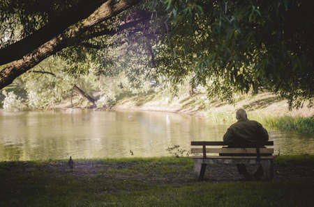 Old man siiting on bench in the park.