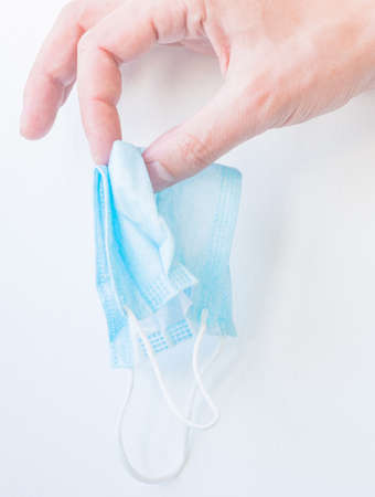 Crush the medical blue disposable mask on a white background with your hand
