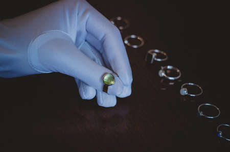 a jeweler examines a piece of jewelry in a white gloveの写真素材