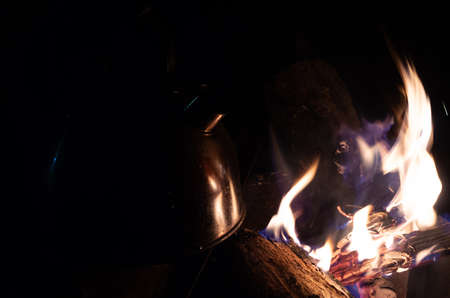 Old aluminum kettle boiling on charcoal or firewood stove with steam