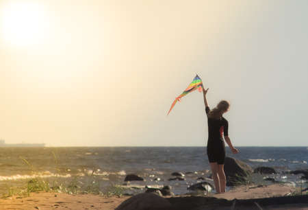 A girl launches a kite on the beach on a Sunny day
