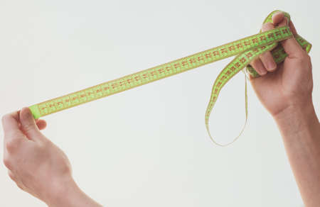 Woman's hand holding green measure tape on white background. Empty place for text, logo or object.