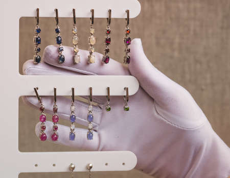 A white-gloved hand holds the earrings. Jewelry made of natural stones.の写真素材