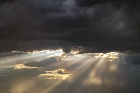 A ray of light through the clouds. Rays of light breaking through dark clouds, a dramatic sky with...