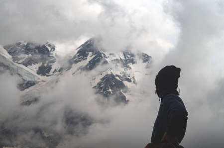 A sporty girl looks at the snowy peaks of the mountains. Extreme weather in the highlands. The concept of hiking and traveling.の写真素材