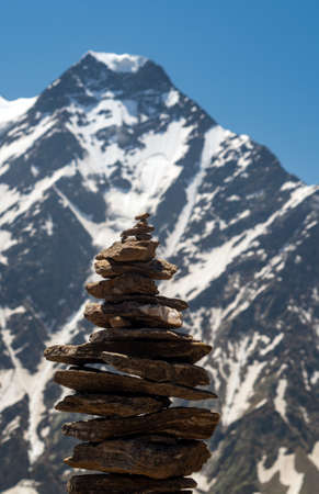 Balance of stones. Balancing stones on the top of boulder. Close up. Balance of stones on a blue sky and mountains background with a copy space. Stones balance, sustainability concept. Close upの写真素材