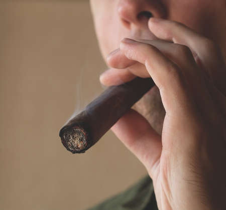 A man smokes a Cuban cigar. Close-up of a smoking cigar.の写真素材
