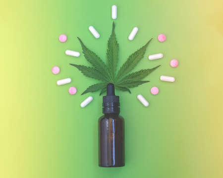 CBD pills. Group of CBD capsules and pink cannabidiol pills and hemp leaves on a green background. Assorted medical cannabis products. Medical marijuana concept. Close upの写真素材