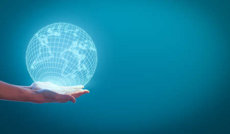 Woman's hands holding the earth globe on a blue background. Global business concept.の写真素材