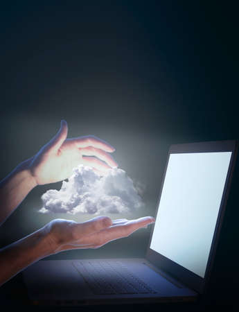 Female hands hold clouds from the laptop screen. cloud computing concept. Cloud storage service concept, data safe keeping, data connection from anywhere. mockup.の写真素材