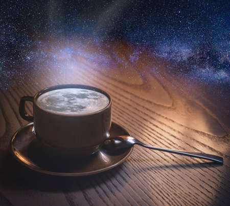 a cup of coffee with the moon and clouds on the background of the night sky. copyspace. The concept of inspiration and creativity.の写真素材