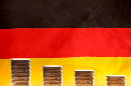 Stacks of gold coins in front of flag of Germany symbolizing crisis in economy of the country. Regression of the economy conceptの写真素材