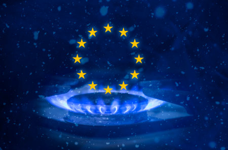 Energy crisis in Europe. The flame of a gas burner against the background of the flag of the...