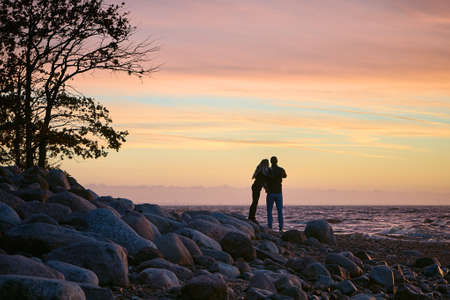 Silhouette of a romantic couple at the seaside enjoying the sunset and taking pictures.