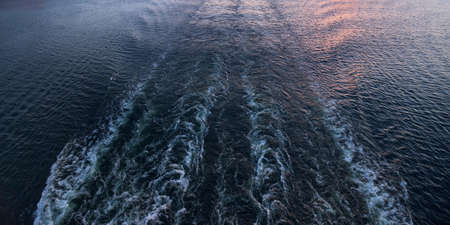 Waves and foam, sea water and rear view to ocean and sunset from cruise ship.