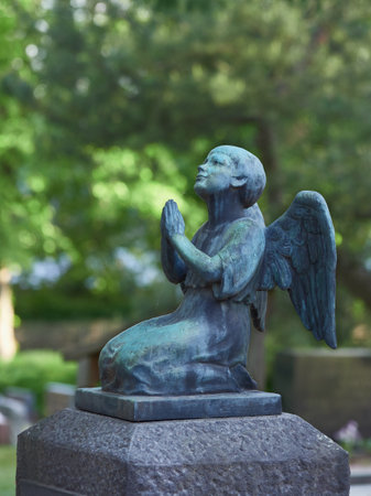 Sculpture of praying angel with wings over grave in European cemetery in Finland.の写真素材