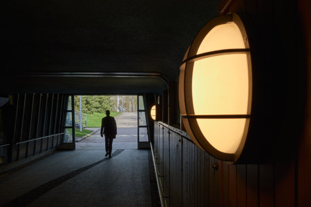 Exit from a pedestrian underpass in the Finnish town of Kerava: lamp on the wall, silhouette of a person.の写真素材