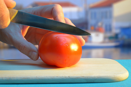 chopping a tomato on a cutting board on the harbour at sunsetの写真素材