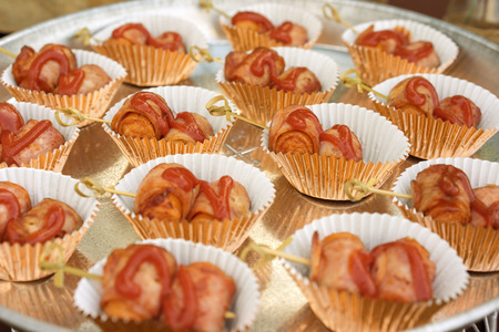 The BBQ canape, the sausages wrapped in bacon on the salver, outdoor picnic food styleの写真素材