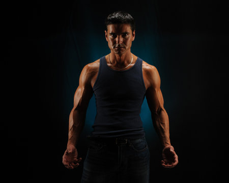 Portrait of a handsome and muscular Asian man posing over black backgroundの写真素材