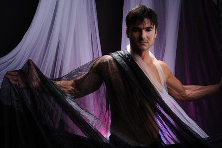 View of a handsome man in the studio with a transparent fabric.の写真素材