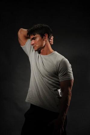 Portrait of a handsome young man in grey t-shirt on black background