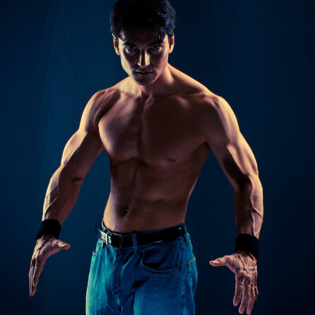 Young man with muscular body posing over dark background.の写真素材