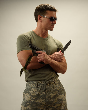 Portrait of young man in military uniform and sunglasses with a knife