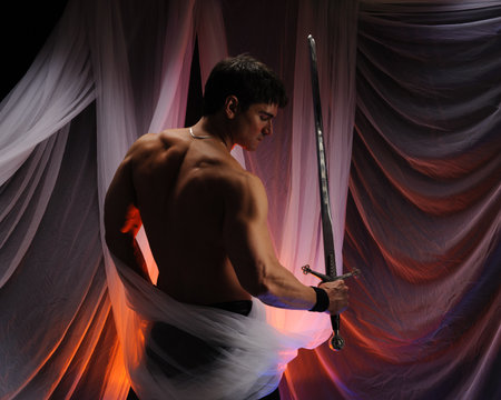 View of a muscled man with a sword in the studio.の写真素材