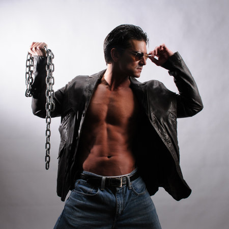 Handsome young man with muscular body and chain in studio.の写真素材