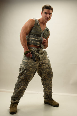 Soldier with a gun on a gray background. Studio shooting.