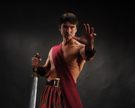 Ancient warrior with sword and scottish tartan cloth on dark backgroundの写真素材