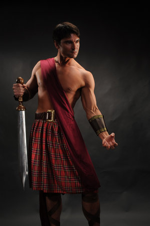 Brutal young man in scottish kilt with swordの写真素材