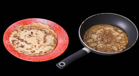Plate with pancakes and frying pan with preparing pancake/ isolated on black の写真素材